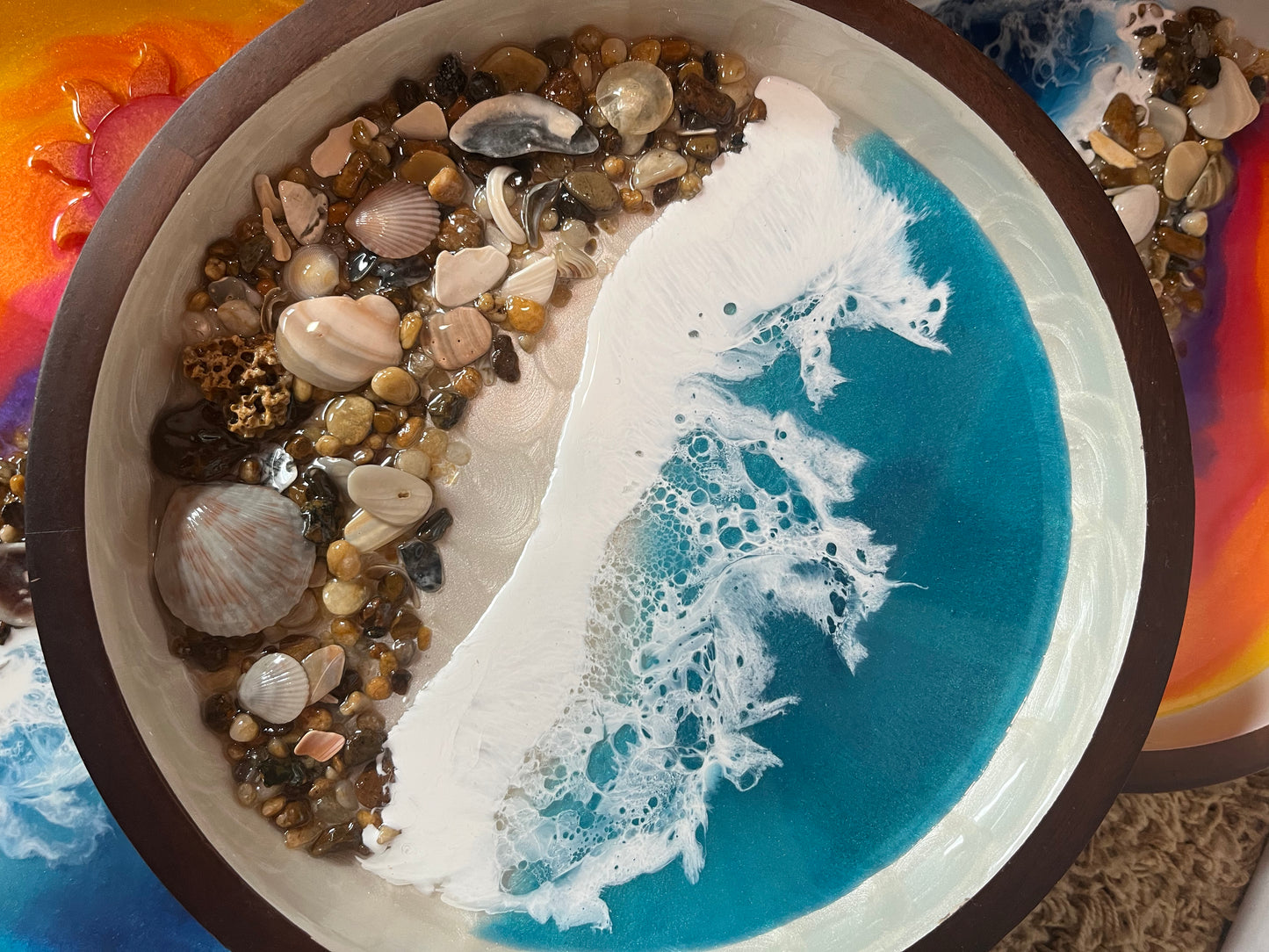Beautifully decorated resin ocean waves inside this 10" round wooden serving tray, Dark wood with white swirls inside. Top half is pretty Teal Resin Ocean Waves crashing on real Outer Banks North Carolina sea shells. Collected from beaches on the OBX.  By Fyre Art Studio Kill Devil Hills NC OBX Resin Artist