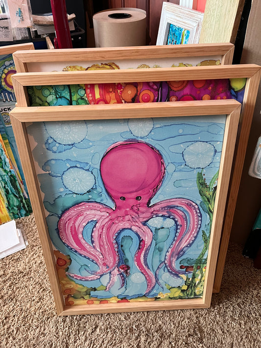 16" x 22" Purple Octopus Canvas Framed Print of original alcohol ink painting by Barbara Newsome.  This print is framed with natural pine wood for a clean beachy feel. Painting is of a cartoonish looking, playful purple octopus floating under the sea.